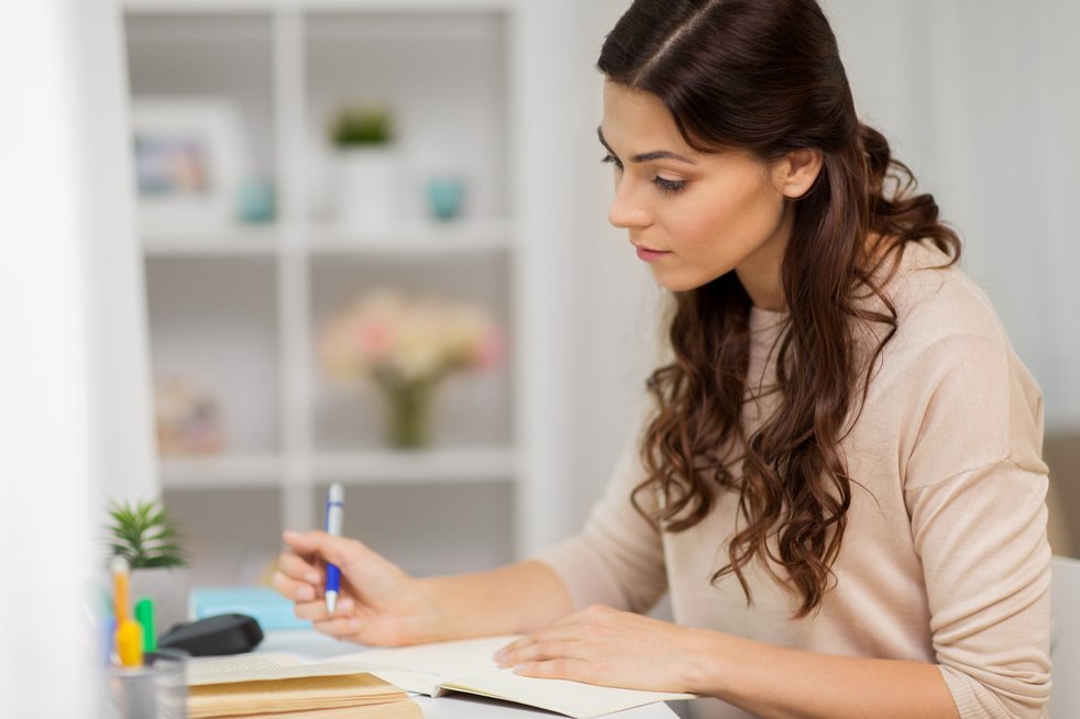 Women writing and deciding, making her list of top five new years resolutions.