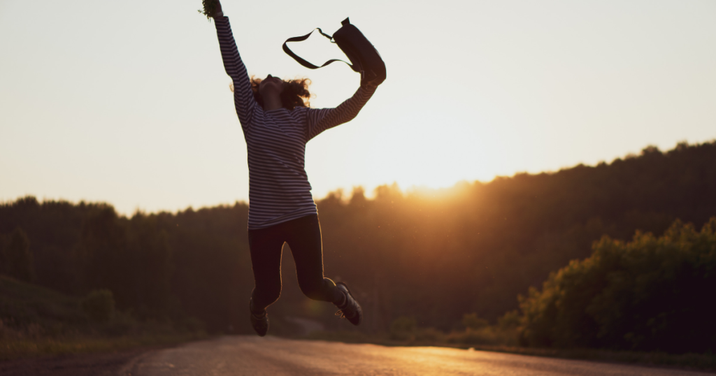 Less Stress Happy Jumping Woman Over Sunrise with Bag on Hand